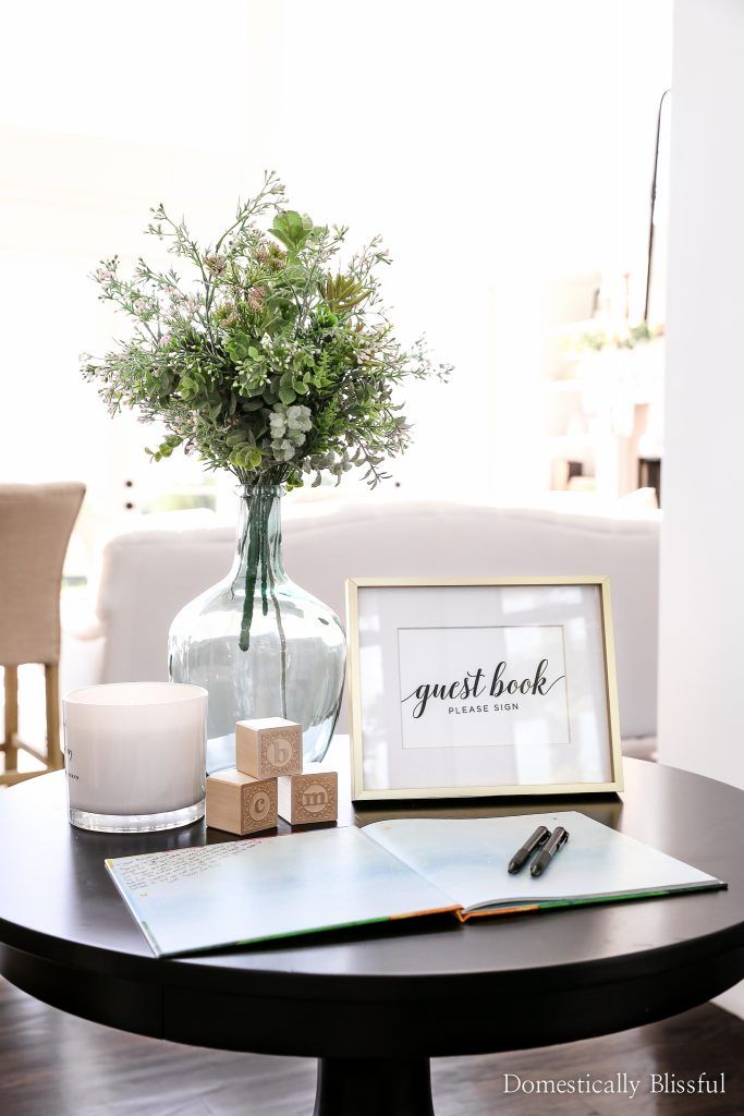 a table with a vase, pen and notepad on it next to a candle