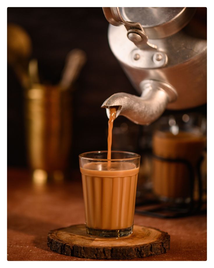 coffee being poured into a glass in front of an espresso machine on a wooden table