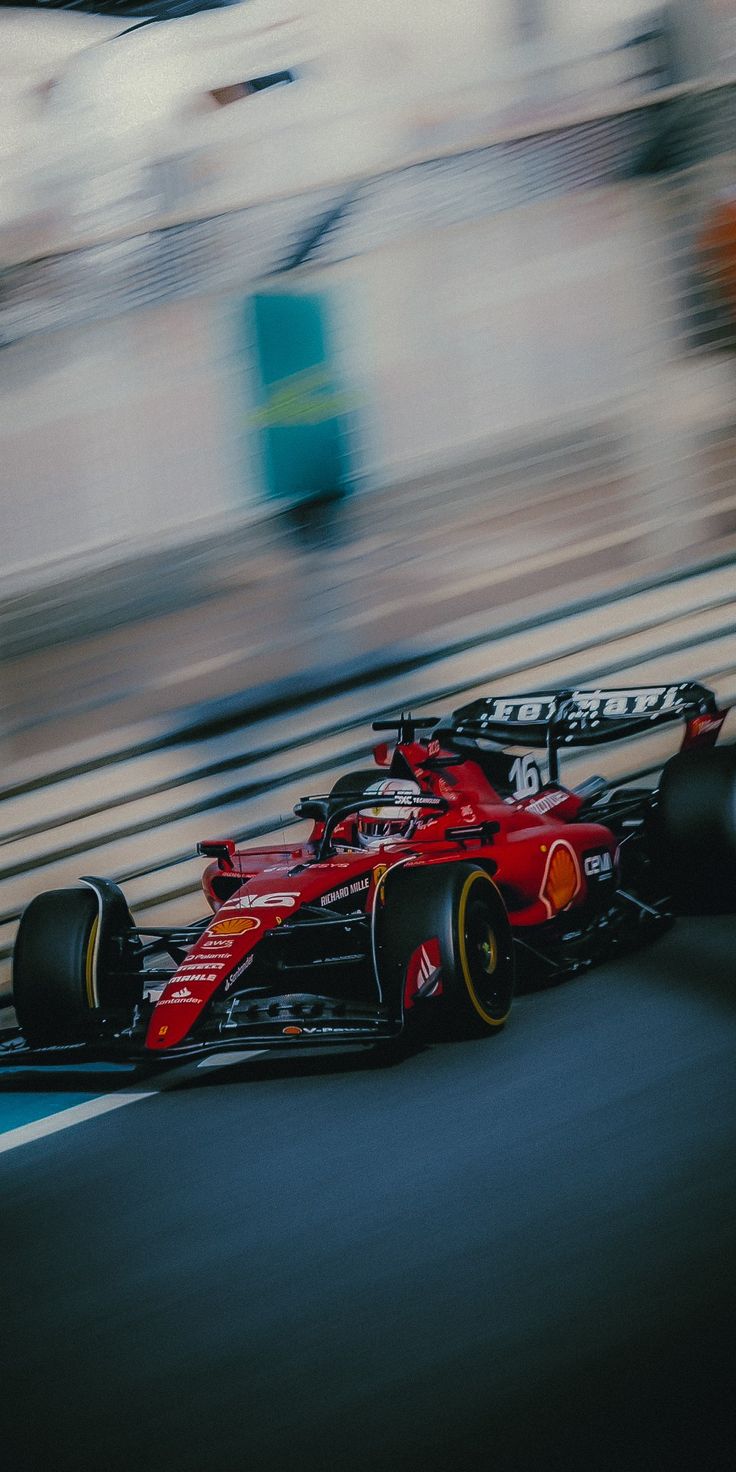 a red race car driving down the track with motion blurry in the foreground