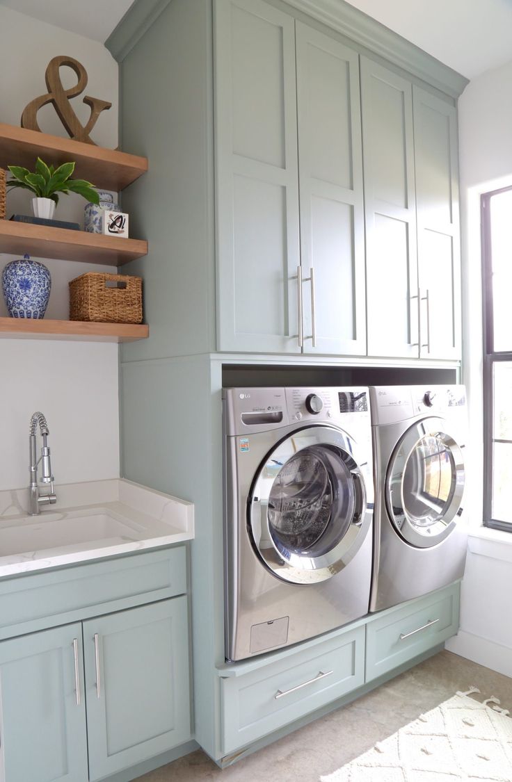 a washer and dryer sitting in a room next to a window with open shelves