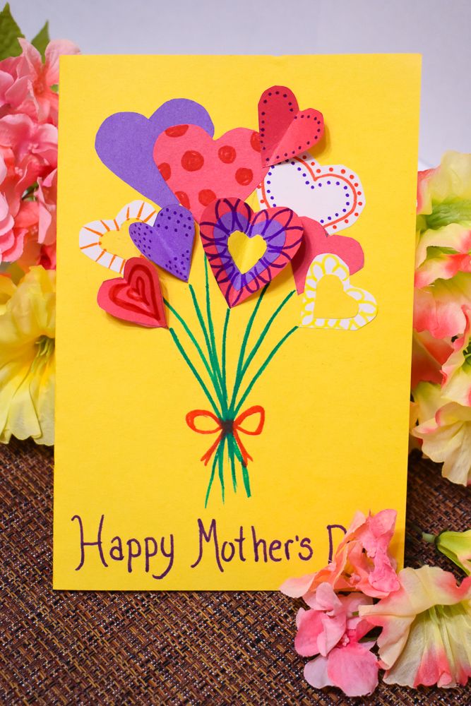 a mothers day card with paper flowers and hearts on it next to pink carnations