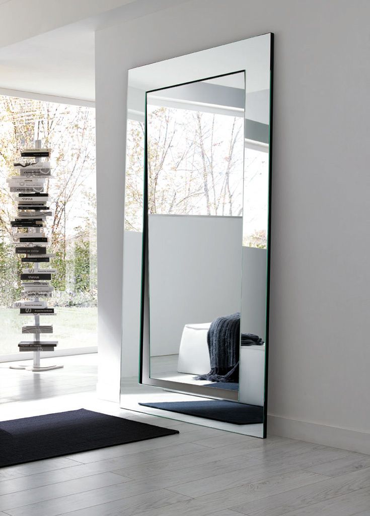 a large mirror sitting on top of a white floor next to a black rug and window