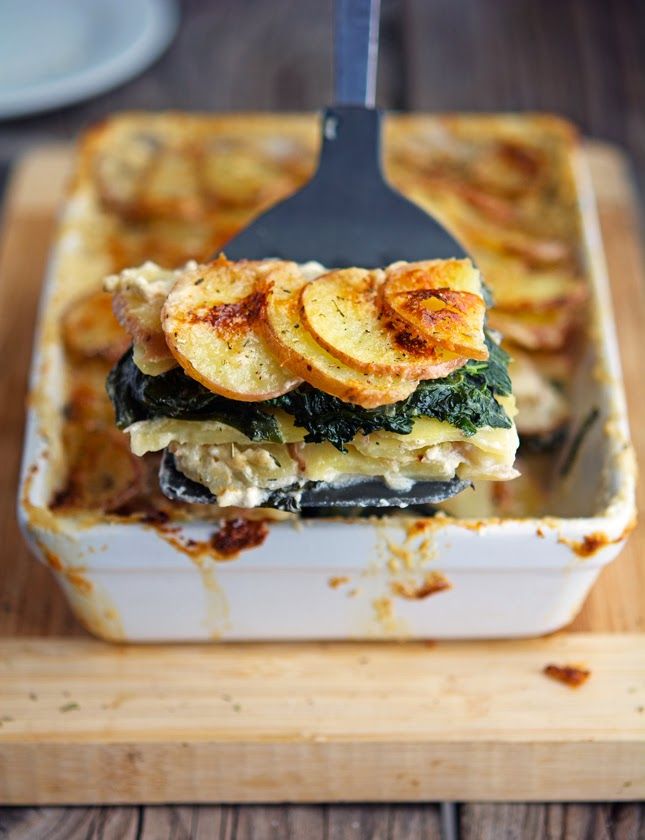 a casserole dish with bananas and spinach in it on a cutting board