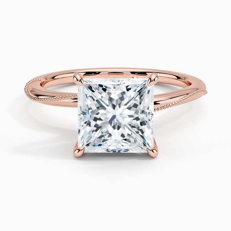 a princess cut diamond ring with pave set diamonds on the band and shoulders in 18k rose gold