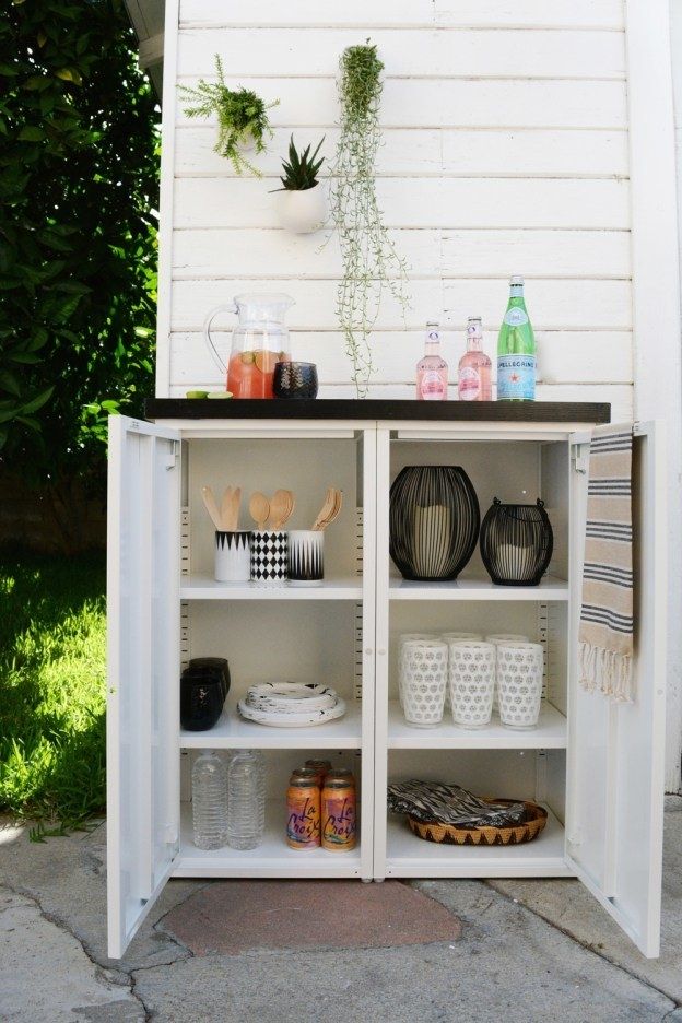 an open cabinet with food and drinks on the top shelf in front of a house