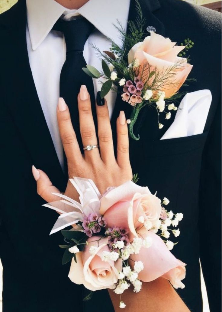 a close up of two people wearing boutonnieres with flowers on their fingers