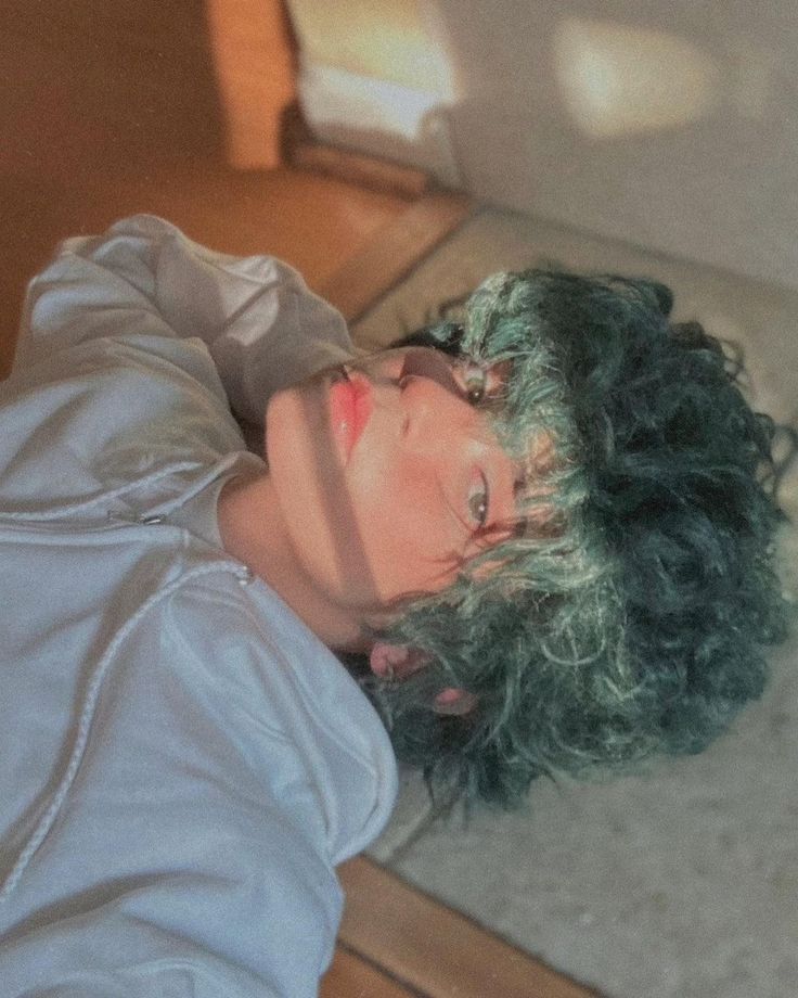 a woman with green hair laying on the floor