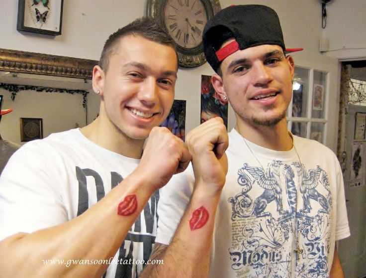 two young men standing next to each other with tattoos on their arms and wristes