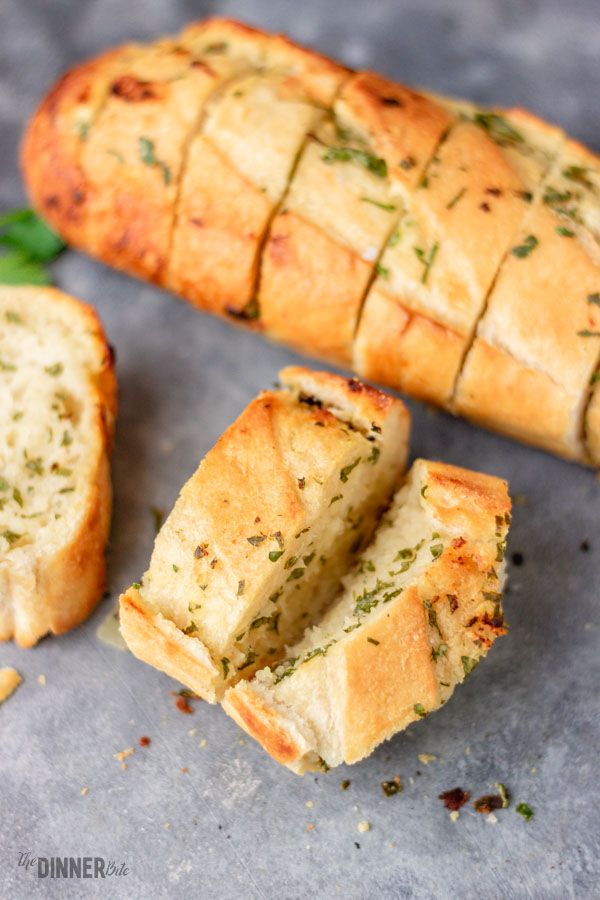 two pieces of bread with herbs on top and one piece cut in half to show the inside