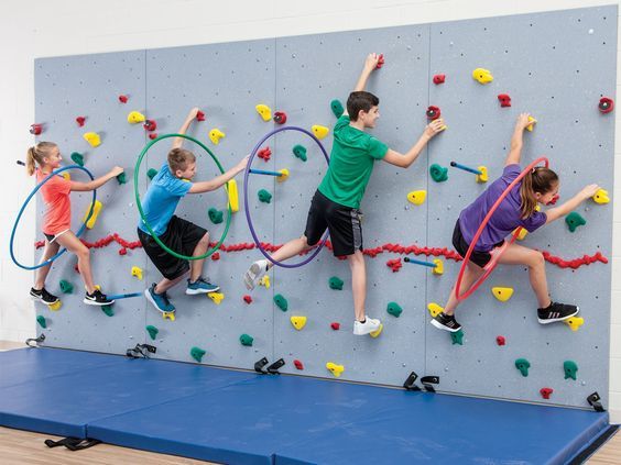 three children are climbing on the wall with their arms in the air and holding onto ropes