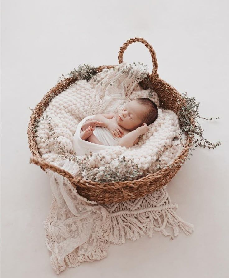 a newborn baby is curled up in a basket