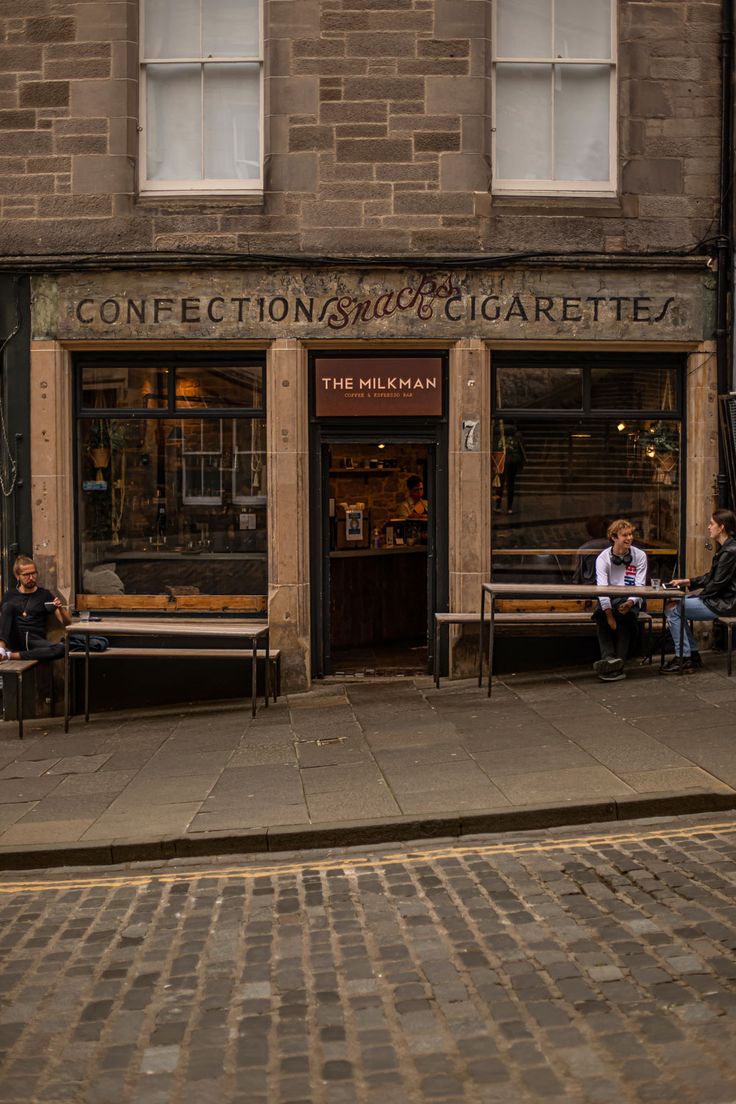 two people sitting on benches in front of a building