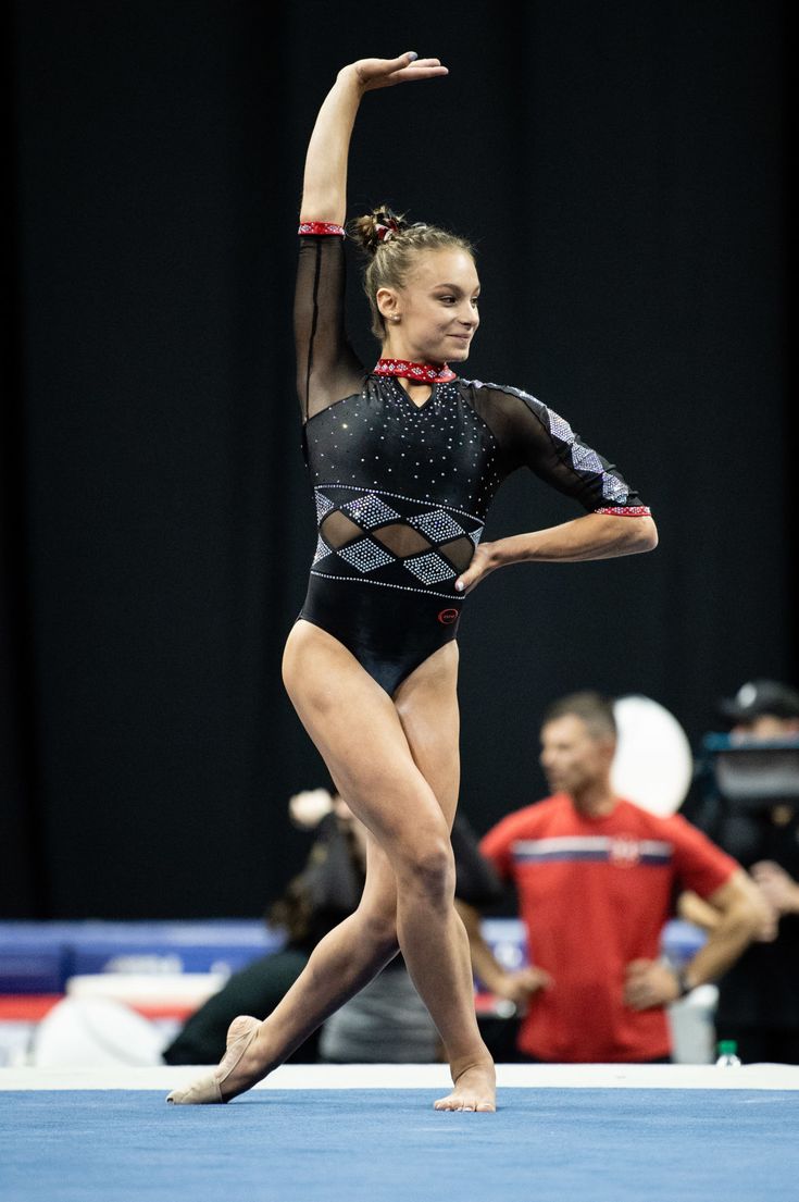 a woman in a black leotard is doing gymnastics