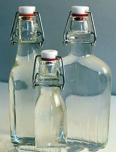 three glass bottles with candy canes in front of them