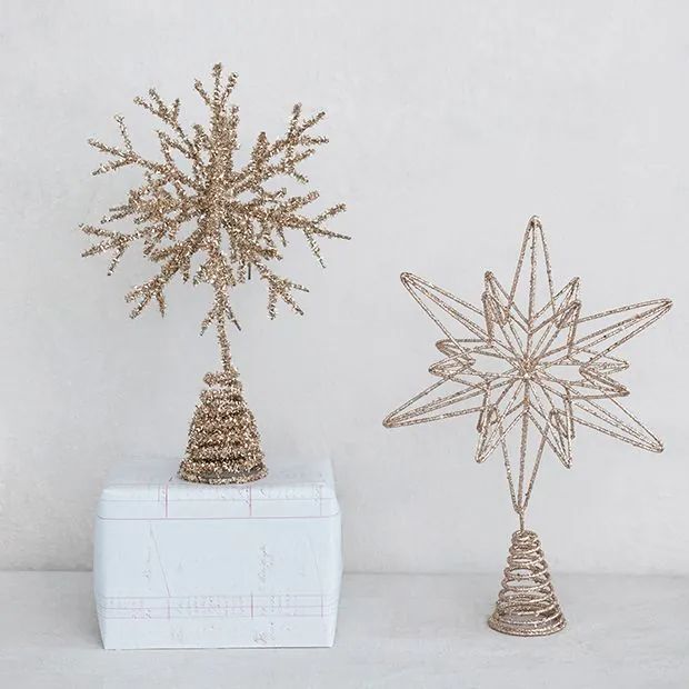 two small gold snowflakes sitting next to each other on a white table top