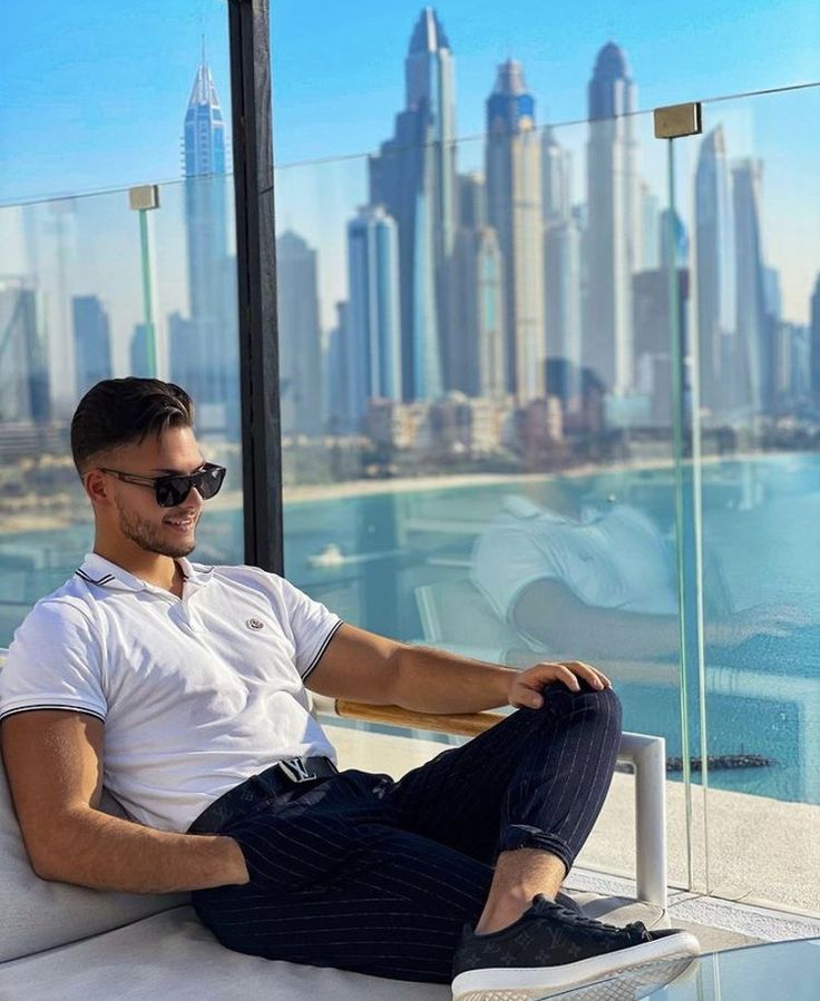 a man sitting on top of a white couch in front of a cityscape