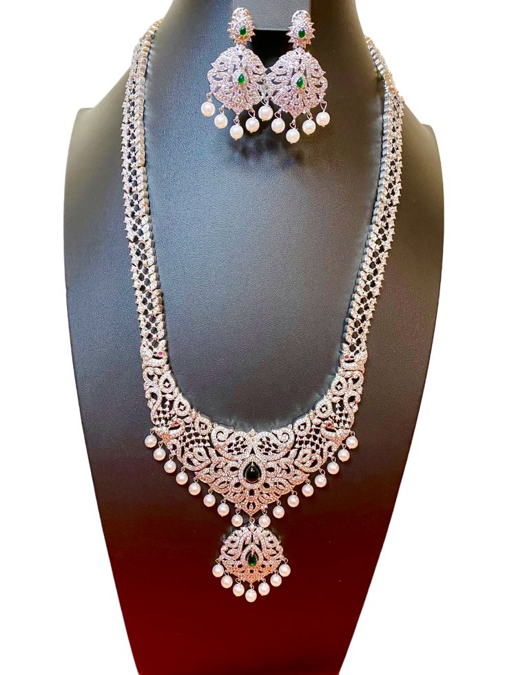 Elevate any occasion with our South Indian Haaram Necklace, adorned with sparkling CZ American Diamonds. Perfect for weddings, parties, and as a luxurious gift for that special someone. Enhance your Indian ensemble, whether it be a traditional silk saree or a glamorous gown. Make a statement with elegance and grace. This jewellery set includes a necklace and matching earrings. Jewellery Care- Keep the jewellery dry, avoid contact with perfumes and water. Elegant Silver Necklaces For Eid, Traditional Bridal Necklace With Diamond Accents For Festive Season, Festive Bridal Sets With Elegant Design For Party, Elegant Bridal Sets For Eid, Festive Party Bridal Sets With Elegant Design, Celebration Bridal Necklace With Stone Work And American Diamond, Heavy Bridal Necklace For Festive Formal Occasions, Heavy Bridal Necklace For Formal Festive Occasions, Traditional Bridal Sets With Diamond Accents For Formal Occasions