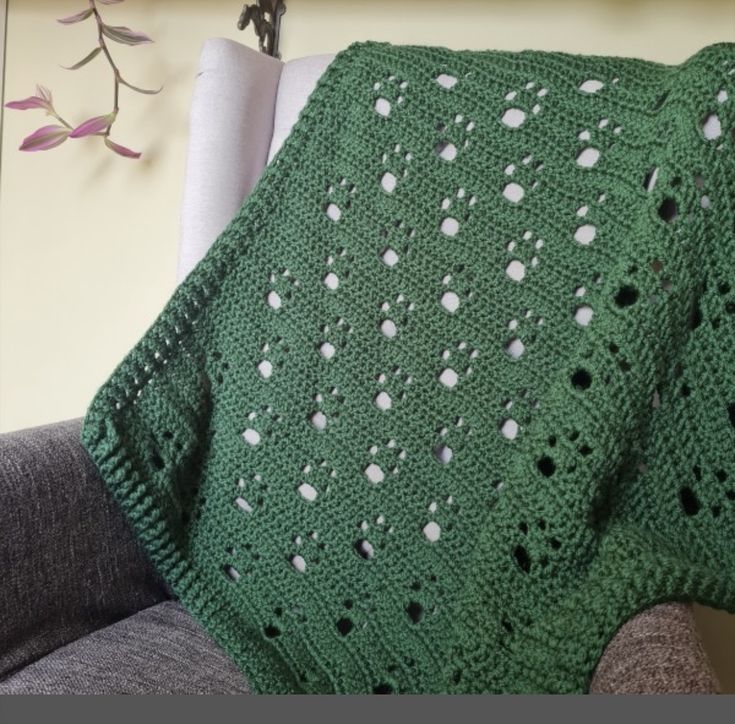 a green crocheted blanket sitting on top of a couch