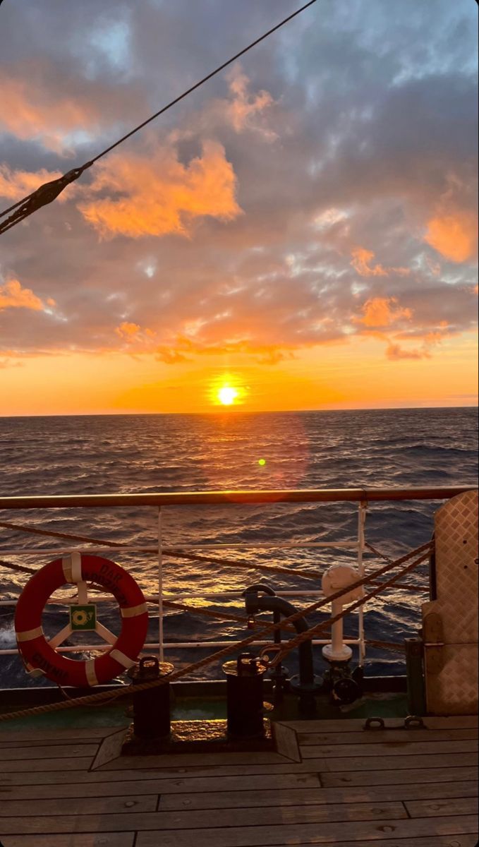 the sun is setting over the ocean as seen from a deck on a cruise ship