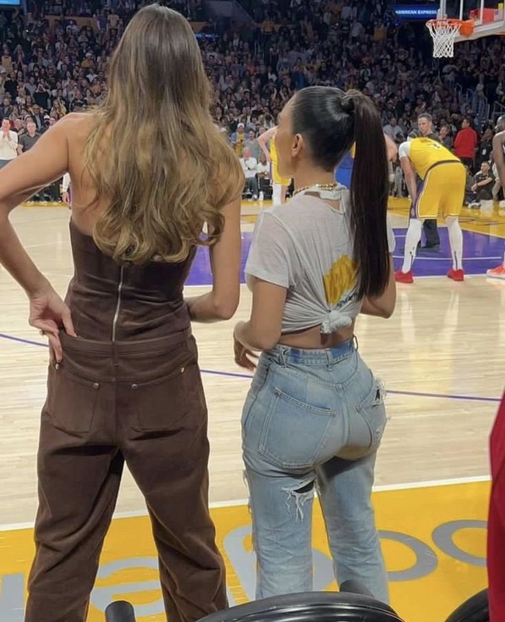 two women standing on top of a basketball court with their backs turned to the camera