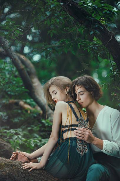 two people sitting on a tree branch in the woods