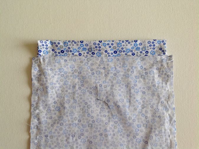 a piece of cloth with blue and white flowers on it sitting on a table next to a wall