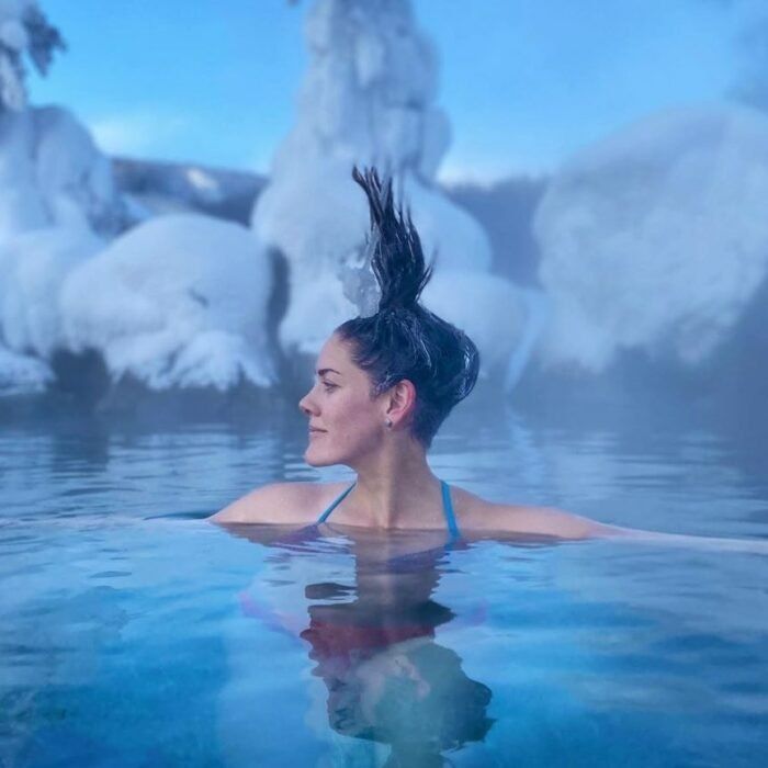 a woman is floating in the water with her hair up