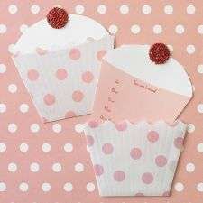 two paper cupcakes with pink polka dots on a pink and white tablecloth