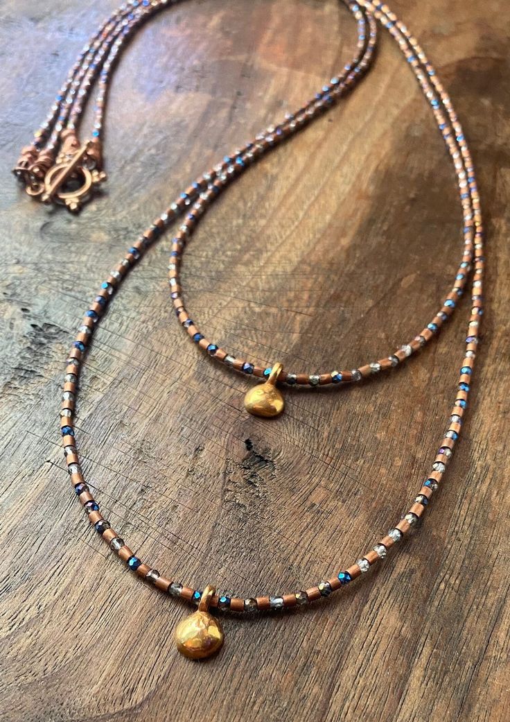 Double trouble!  This double stranded necklace is made from Nepalese copper, sparkly faceted glass, and vermeil charms!  It's long and lightweight and feels great on! It's definitely a statement necklace that wants to be worn!  The shortest strand is 26" long and the longest is 28.5".  Necklace is finished with a copper toggle clasp. Gold Double Strand Spiritual Beaded Necklace, Spiritual Gold Double Strand Beaded Necklace, Artisan Multi-strand Gold Beaded Necklaces, Artisan Gold Multi-strand Beaded Necklaces, Artisan Gold Multi-strand Beaded Necklace, Artisan Multi-strand Gold Necklace, Gold Jewelry With Faceted Beads And Copper, Gold Copper Jewelry With Faceted Beads, Gold Double Strand Necklaces With Spacer Beads