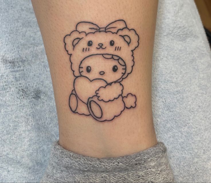 a small tattoo on the ankle of a girl with a teddy bear in her lap