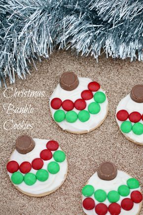 four decorated cookies sitting next to a christmas tree