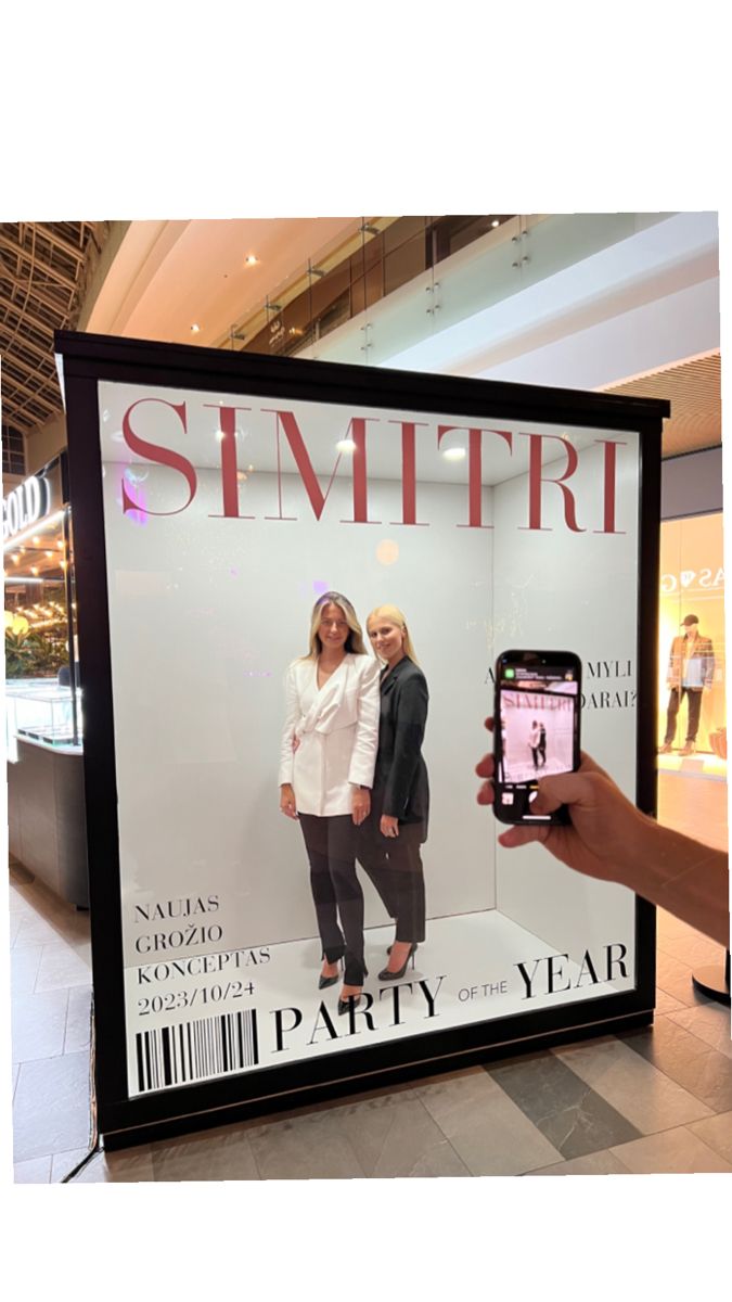 a person holding up a cell phone in front of a advertisement for a women's clothing store