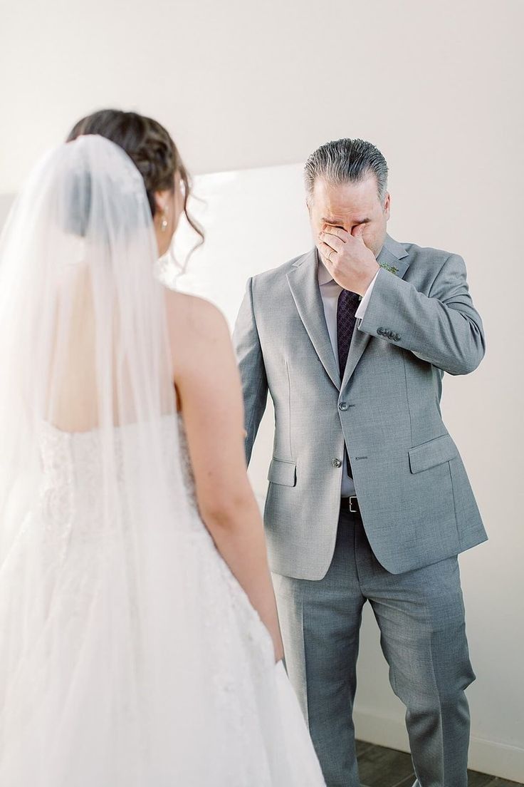 a man in a suit and tie standing next to a woman wearing a wedding dress