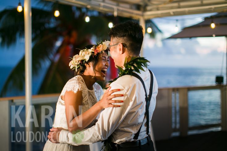 a bride and groom dance together under an awning at their wedding reception in front of the ocean