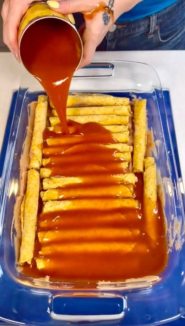 a person pouring sauce over french fries in a blue container