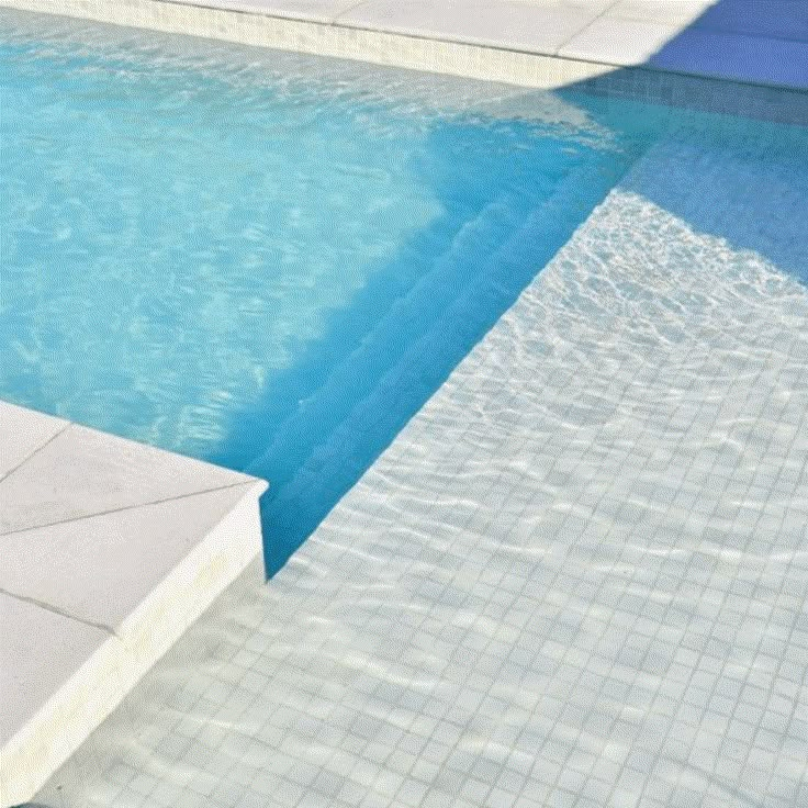 an empty swimming pool with blue water and white tiled flooring is pictured in this image