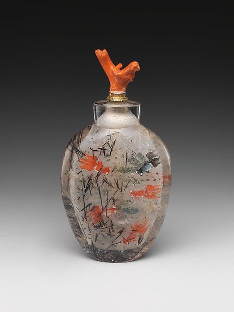 a glass vase with an orange bird on it's top and some paint splatters all over the bottom