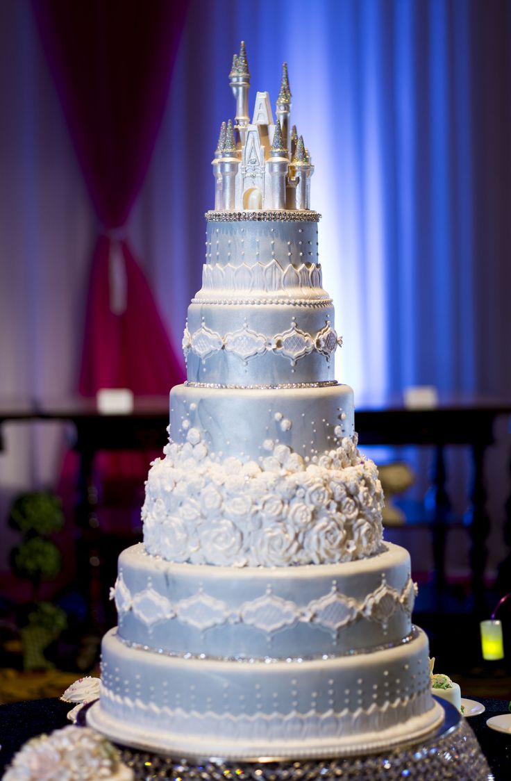 a wedding cake with white frosting and castle decorations on the top is sitting on a table