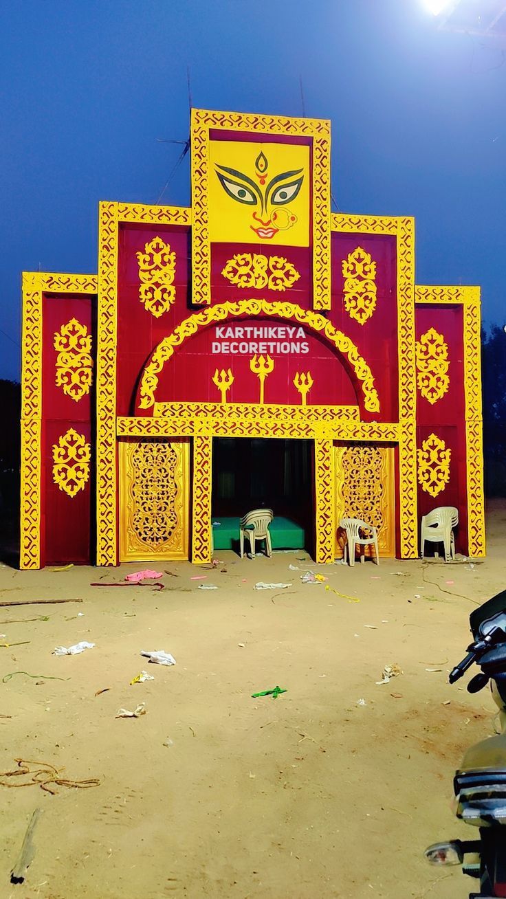 a motorcycle parked in front of a red and yellow building with decorations on it's sides