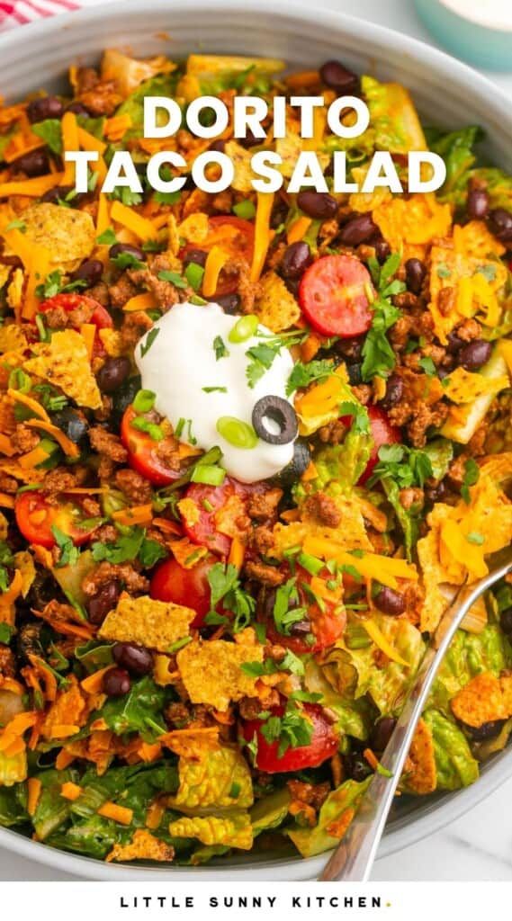 a white bowl filled with taco salad and topped with sour cream