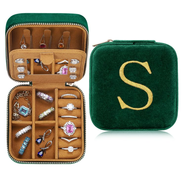 a green case filled with lots of different types of jewels and jewelry on top of a white surface