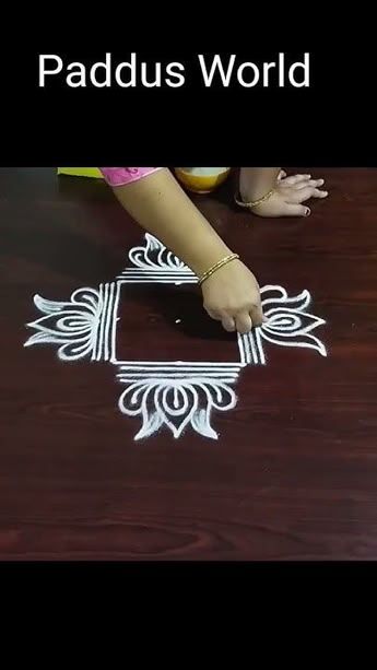 a woman is drawing on the floor with chalk and white paint in front of her