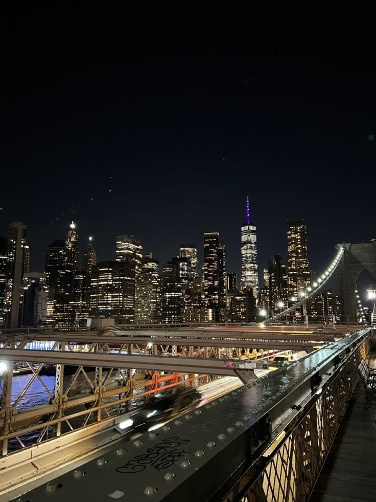 the city skyline is lit up at night with lights on and cars driving down the street