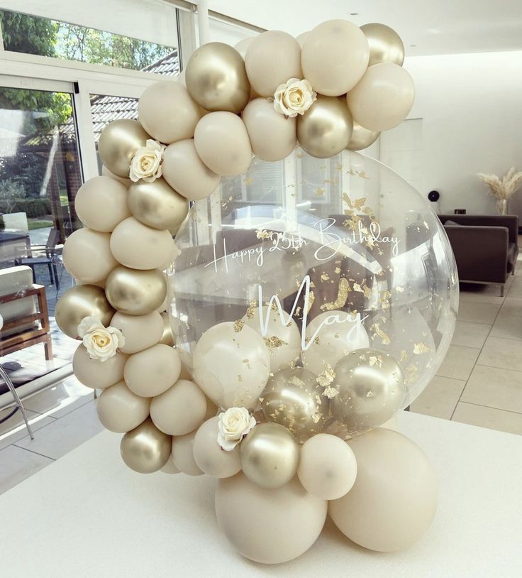 a table topped with white and gold balloons in the shape of a clock surrounded by flowers