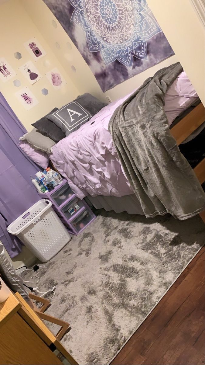 a bed room with a neatly made bed next to a purple wall hanging on the wall