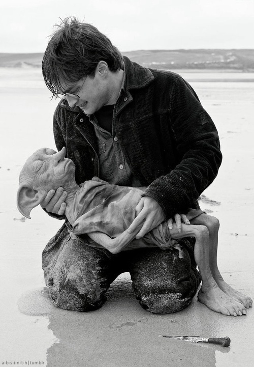 a man kneeling down next to a little boy on the beach with an animal in his lap