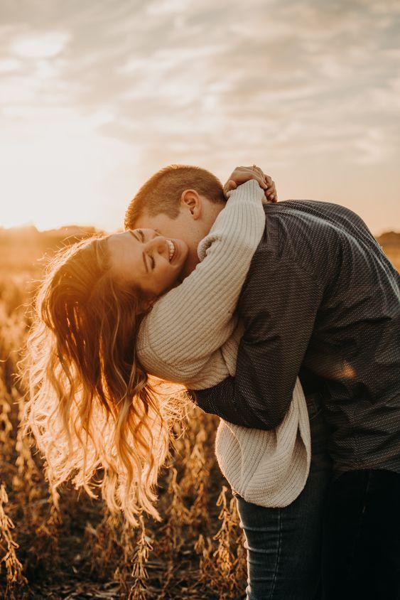 a man and woman embracing in the middle of a wheat field at sunset with the sun behind them