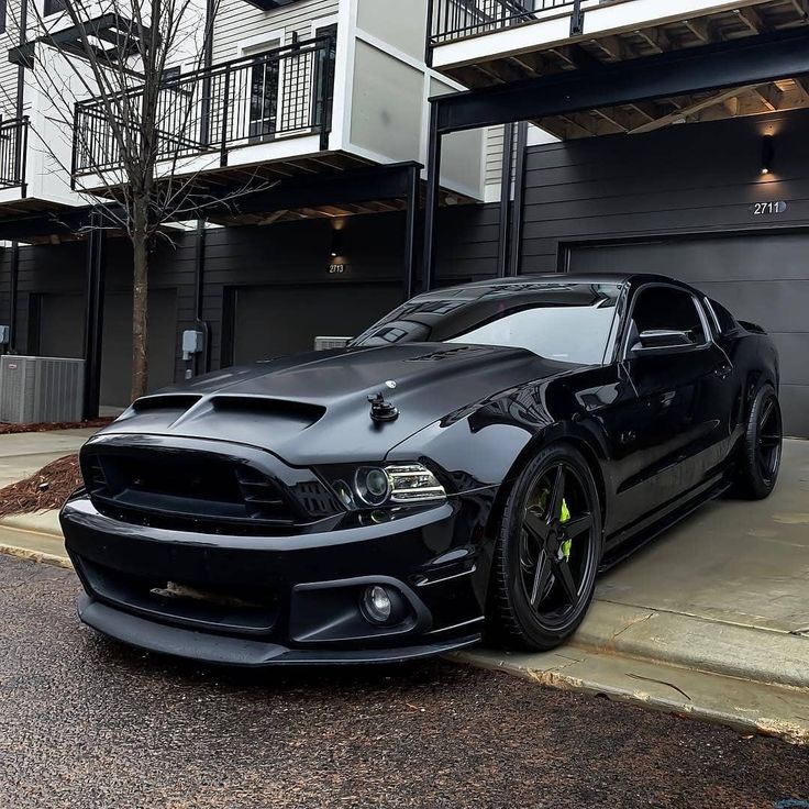 a black mustang parked in front of a building