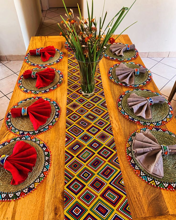 the table is set with place mats, napkins and flowers in a vase on it