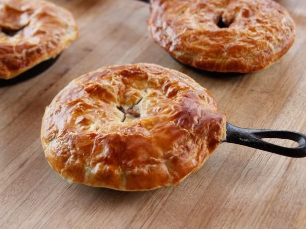 several baked pastries sitting on top of a wooden cutting board